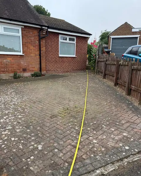 Before: a grey block paving driveway covered in lichen spots and weeds.
