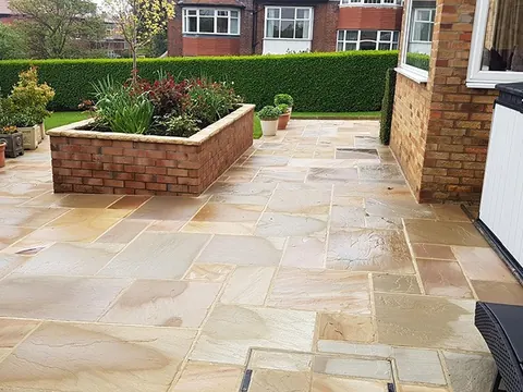 A sandstone patio after cleaning, the flags bright and free of moss.