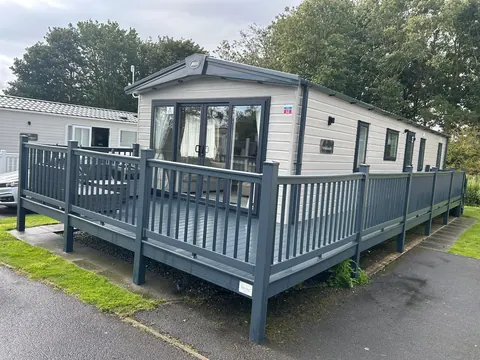 A clean static caravan with grey decking on a holiday park.