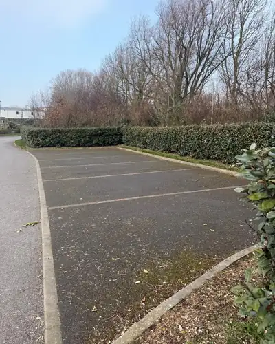 Before: a faded, grimy tarmac car park with moss along the kerbs.